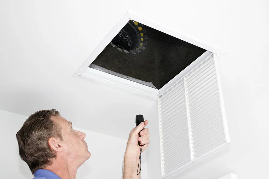 Man Inspecting Air Intake Duct, Male looking up into a ceiling air intake duct